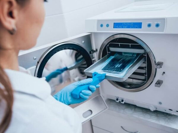 Profissional usando luvas azuis para inserir ferramentas de manicure seladas em autoclave, garantindo a biossegurança e o protocolo de Manicure de Saúde do The Nails.